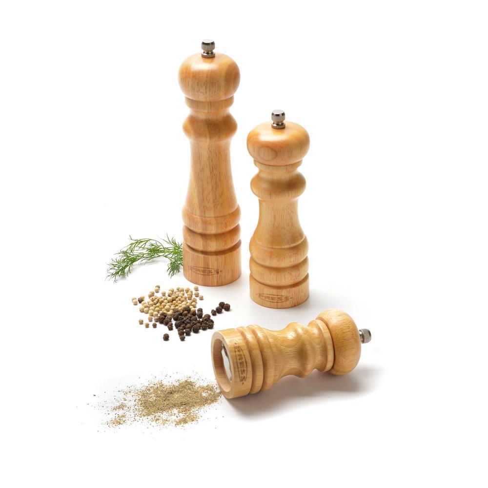 Molino de pimienta y molinillo de sal en una mesa de madera con molinillo  de otros productos en manos humanas sobre fondo de piedra gris